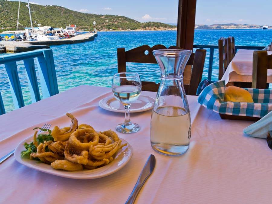 Credit: Banet / Bigstock Seaside taverna with fried squid and wine on the table